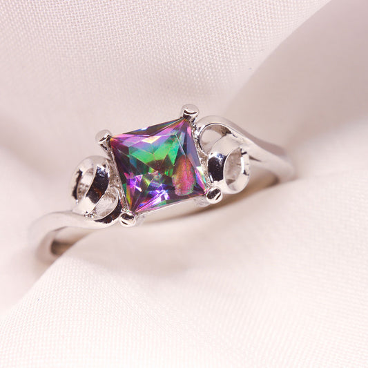Stainless steel ring in silver color with a central multicolored square zircon crystal held by silver swirls.